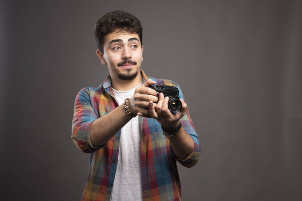 young man with a camera on a gray background - Photo, Image