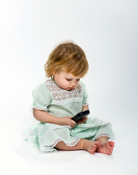 Cute little girl with mobile phone on white background - Photo, Image
