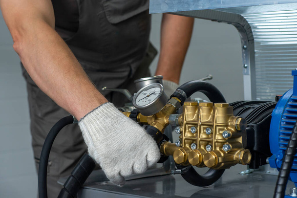 Die Hand eines Mannes in einem weißen Handschuh dreht sich an einem Set mit Manometer zur Prüfung von Hochdruck-Hydraulikschläuchen. Ein Mann in Uniform testet Hochdruckschläuche. Rohrprüfsystem. - Foto, Bild