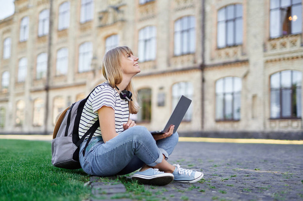 Щаслива студентка в університетському містечку використовує ноутбук влітку
 - Фото, зображення