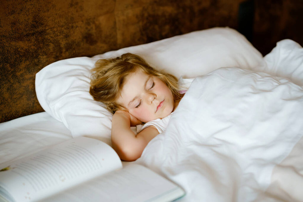 Χαριτωμένο κοριτσάκι που κοιμάται στο κρεβάτι. Αξιολάτρευτο παιδί που ονειρεύεται, υγιή ύπνο παιδιών τη μέρα. Βαθύς ύπνος νηπίου. Τα παιδιά ξεκουράζονται. - Φωτογραφία, εικόνα
