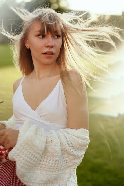 Módní mladá fena pózující v bílém svršku a svetru při západu slunce - Fotografie, Obrázek