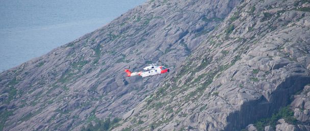 Helikopter teljesítő életmentő légi lift felett sziklás hegy tetején - Fotó, kép