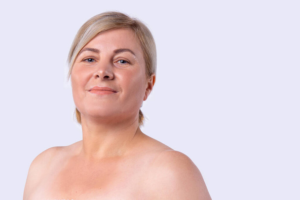 Blonde hair cut woman with pleasant appearance smiling posing at a camera with bare shoulders. - Foto, afbeelding