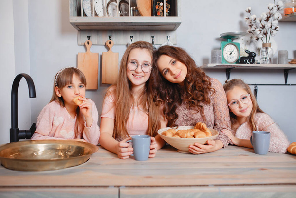 Cute sisters standing in a kitchen and eats buns - Foto, Imagen