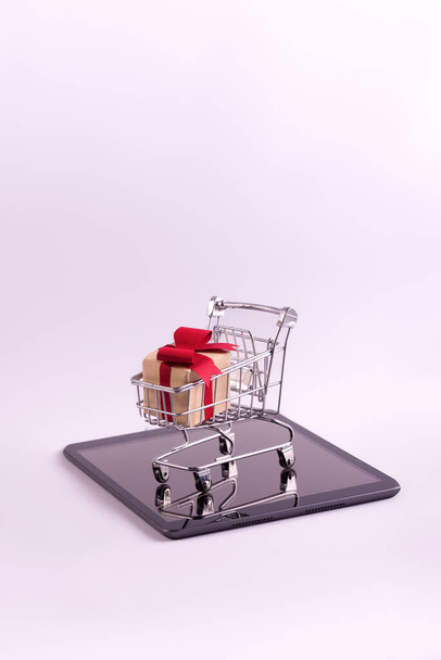 İnternetten alışveriş ve e-ticaret konsepti fotoğrafı. Tabletteki hediye kutularıyla dolu alışveriş arabası.. - Fotoğraf, Görsel