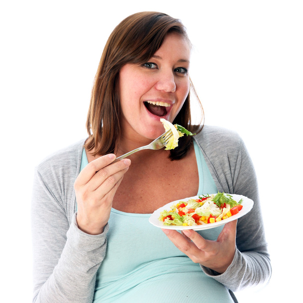 Fiatal nő evés a finom saláta és mosolyog. Ellátja a szájba a villát - Fotó, kép