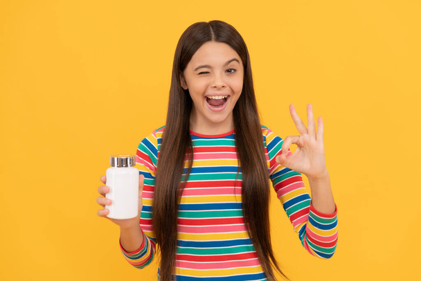 girl with natural pill products. presenting vitamin product. happy child with pill jar. - Fotó, kép