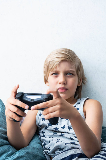 Junge hält Steuerknüppel in der Hand, spielt Videospiel zu Hause. - Foto, Bild