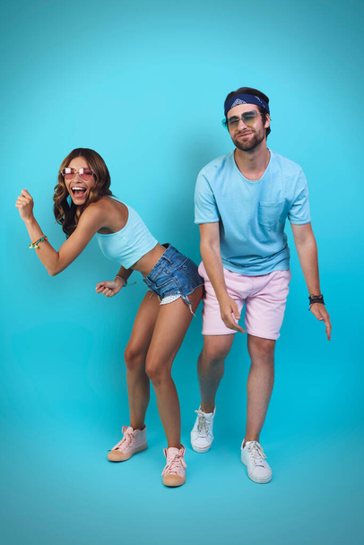 Full length of beautiful young couple having fun while standing against blue background - Foto, Imagem