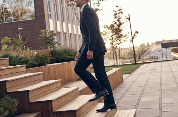 Confident mature man in full suit walking up by staircase outdoors - Φωτογραφία, εικόνα