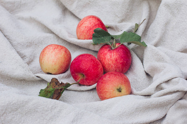 Червоні яблука лежать на легкій скатертині. Осінній настрій, осінні вібрації та кольори, модний осінній стиль, урожай
 - Фото, зображення