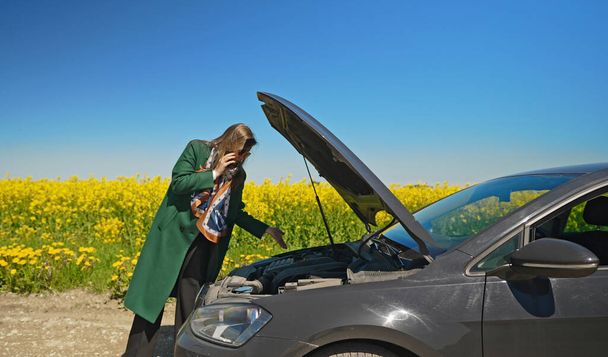 Donna vicino a un'auto rotta che chiede aiuto. - Foto, immagini