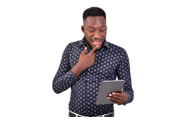 mladý vousatý muž stojící na bílém pozadí komunikující pomocí tabletu - Fotografie, Obrázek