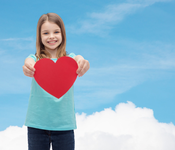 smiling little girl giving red heart - Фото, изображение