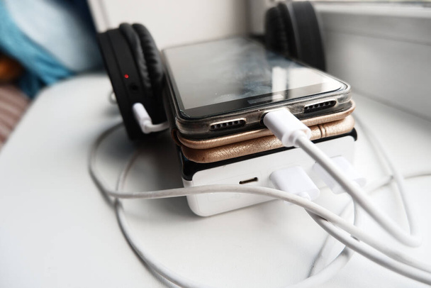 telefone celular e fones de ouvido bluetooth são carregados usando powerbank. - Foto, Imagem