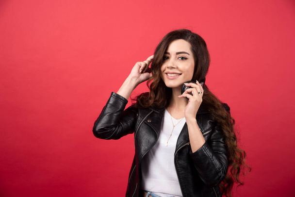Young woman taking off headphones and posing on a red background. High quality photo - Photo, Image