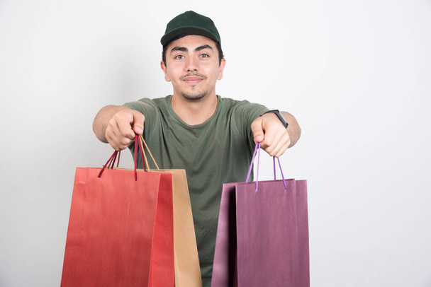 Egy fiatalember fehér hátterű bevásárlószatyrokkal a kezében. Kiváló minőségű fénykép - Fotó, kép