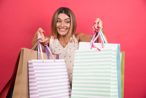 赤い背景に幸せな表情でショッピングバッグを運ぶ女性。高品質の写真 - 写真・画像