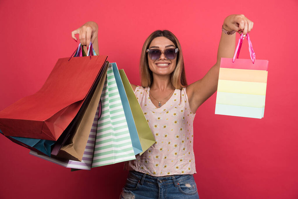Mujer mostrando sus bolsas de compras sobre fondo rojo. Foto de alta calidad - Foto, imagen