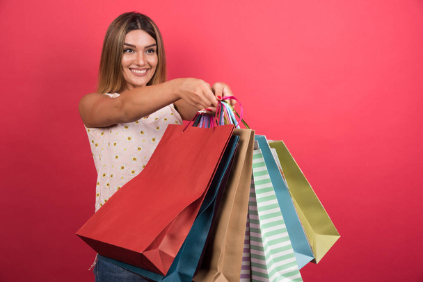 Frau zeigt Einkaufstaschen auf rotem Hintergrund. Hochwertiges Foto - Foto, Bild