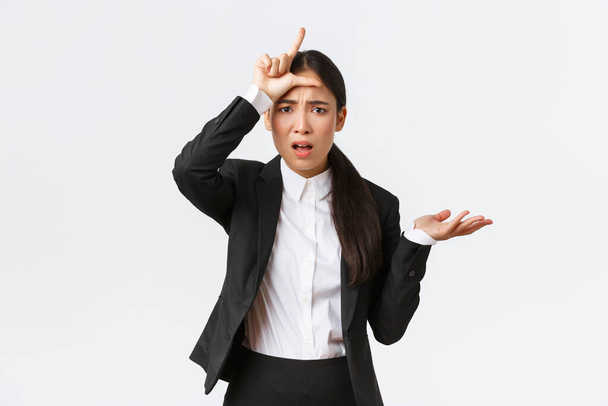 Geïnteresseerde en geïrriteerde Aziatische zakenvrouw schreeuwen werknemer voor falen, tonen verliezer gebaar en het verhogen van de hand in ontsteltenis, kan niet begrijpen waarom zo dom, klagen over witte achtergrond - Foto, afbeelding