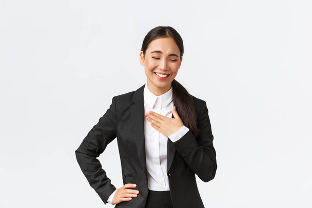 Siyah takım elbiseli profesyonel başarılı iş kadını konuşuyor, gülüyor ve göğsüne dokunuyor. Komik ya da pohpohlayıcı bir şey. İşinde iyi olduğu için övgü alıyor. - Fotoğraf, Görsel