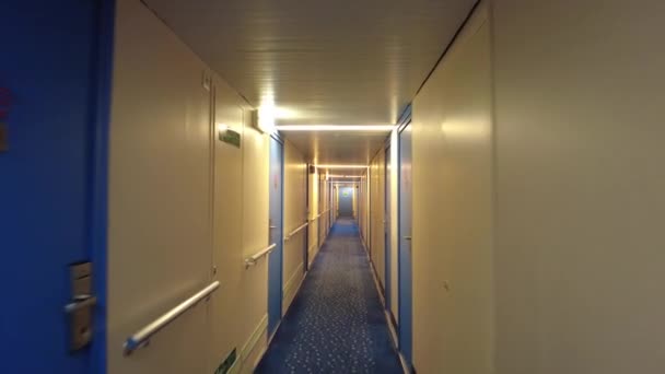 Pov caminando solo en la noche en un largo pasillo del barco iluminado por luces suaves con muchas puertas. - Metraje, vídeo
