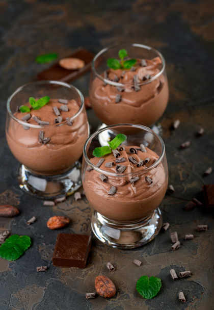 Mousse de chocolate vegano con menta, barra de chocolate y granos de cacao sobre un fondo oscuro. Copiar espacio - Foto, Imagen