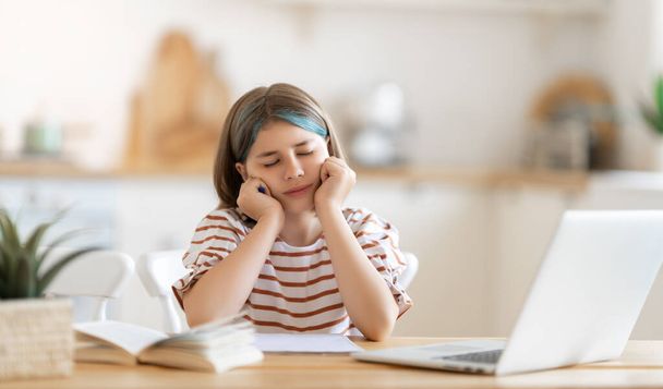Back to school. Unhappy child is sitting at desk. Girl doing homework or online education. - Foto, Imagem