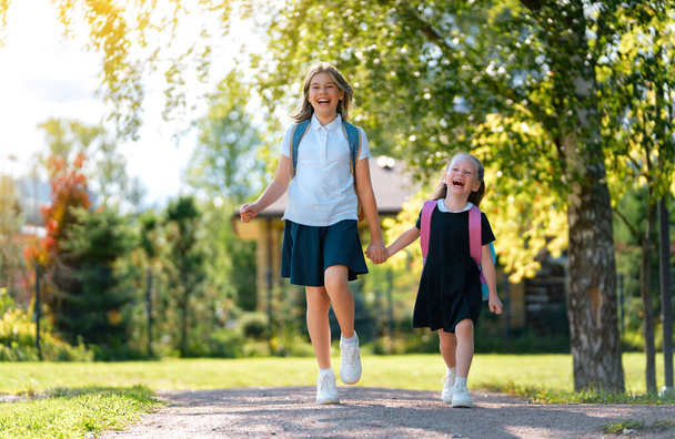Pupils of primary school. Girls with backpacks outdoors. Beginning of lessons. First day of fall.      - Foto, Imagem