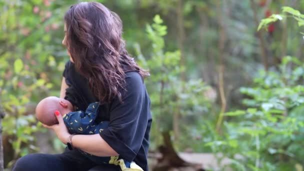 Молода мила мама годує дитину грудним молоком в лісі
 - Кадри, відео