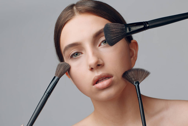 Portrait of young beautiful positive woman with nude make up and brush. - Photo, Image