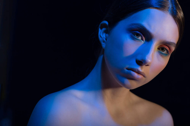 Portrait de jeune belle femme positive avec maquillage nu et lumière colorée - Photo, image