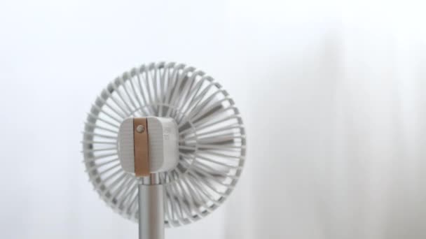 Tarz sahibi beyaz elektrikli soğutma vantilatörü bir yaz günü ev odasında çalışır. Sıcak yaz havası. Arka plan - Video, Çekim