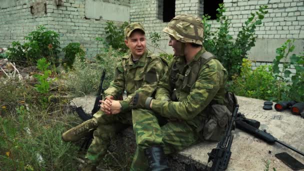 Δύο στρατιώτες κάθονται κουρασμένοι ανάμεσα στα ερείπια και μιλάνε. - Πλάνα, βίντεο
