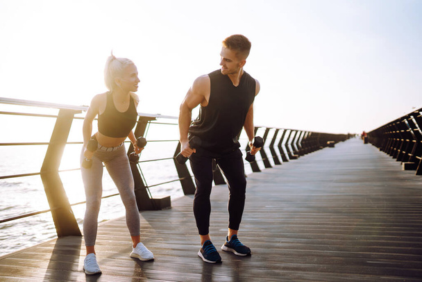 Romantic couple doing sport together at the beach pier. Two sporty athletes doing warming-up excersises. Sport, Active life. - Foto, Imagem
