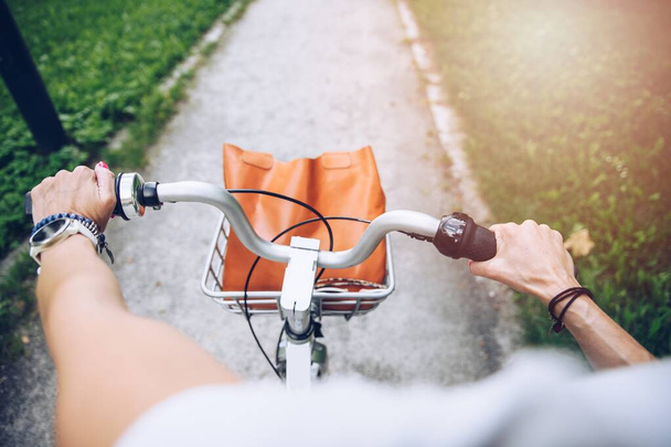 Mujeres manos en el manillar de la bicicleta en el día soleado. Concepto de estilo de vida saludable en la ciudad. - Foto, Imagen