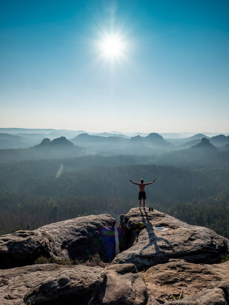 Silhouette maschile senza camicia con braccia sollevate sulla cima tagliente della montagna. Concetto di vita sportiva e attività all'aperto - Foto, immagini