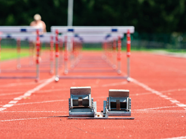 Trening z przeszkodami. Lekkoatletyka Bloki wyjściowe i czerwone tory biegowe na stadionie - Zdjęcie, obraz