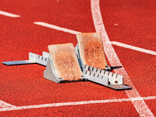 Side view of worn out starting blocks on running tracks. Red running tracks lanes at track and field stadium. Sport accessory. - Photo, Image
