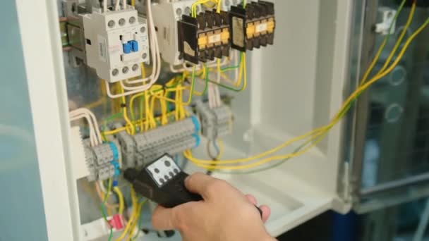 Closeup. Electricians hands testing current electric in control panel. Electrician engineer work tester measuring voltage and current of power electric line in electical cabinet control. - Footage, Video