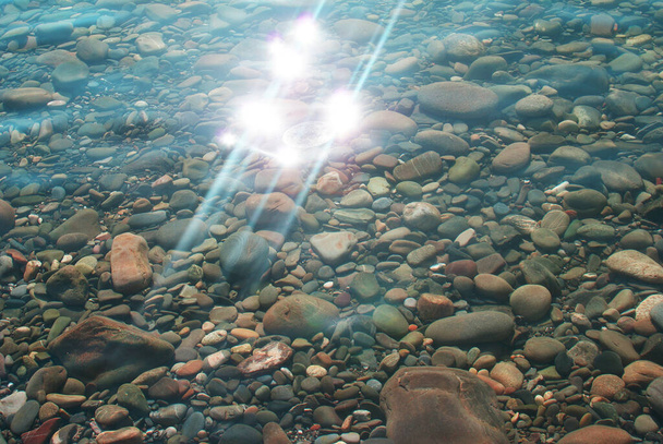 Deslumbramiento del sol en el agua, guijarros en el fondo del mar, naturaleza. - Foto, Imagen