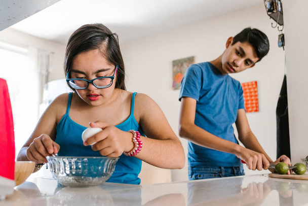 Λατίνα έφηβη με σύνδρομο Down και ο αδελφός της να μαγειρεύει στο σπίτι, στην έννοια της αναπηρίας στη Λατινική Αμερική - Φωτογραφία, εικόνα