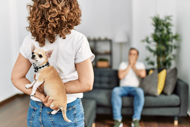 Mulher surpreendendo seu marido com cão adorável em casa. - Foto, Imagem