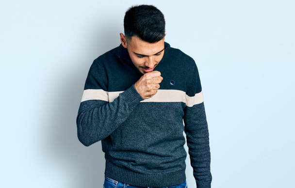Hombre hispano joven con barba que usa suéter casual de invierno sintiéndose mal y tosiendo como síntoma de resfriado o bronquitis. concepto de atención sanitaria.  - Foto, Imagen