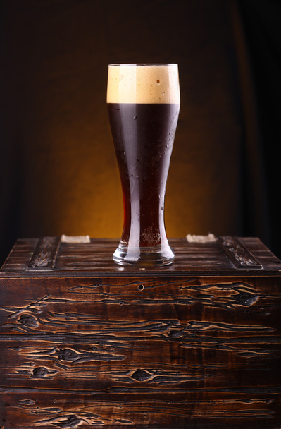 Bicchiere di birra scura su un petto
 - Foto, immagini