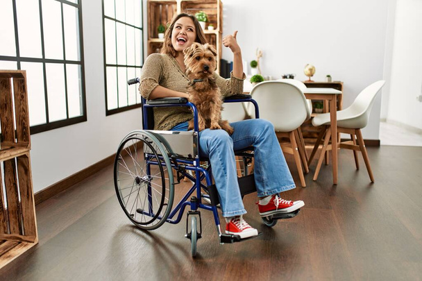 Молодая латиноамериканка, сидящая дома на инвалидной коляске, расслабляется и улыбается с закрытыми глазами, делая медитационный жест пальцами. Концепция йоги.  - Фото, изображение