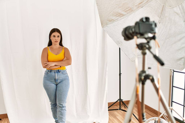 Nuori kaunis latino nainen poseeraa mallina valokuvaus studio skeptinen ja hermostunut, paheksuva ilme kasvot ristissä kädet. negatiivinen henkilö.  - Valokuva, kuva