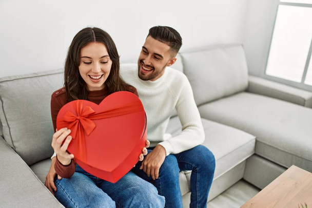 Молода пара іспаномовних посміхається щасливий дивовижний подарунок з валентинкою вдома
. - Фото, зображення